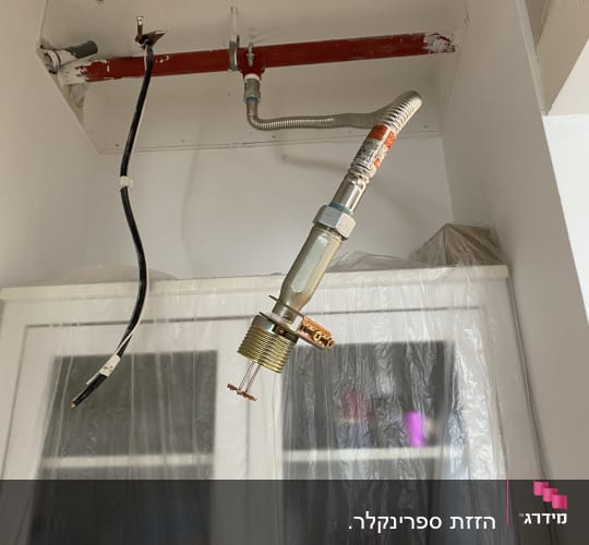 צינור כיבוי אש אדום עם חיבורי מתכת בתקרה